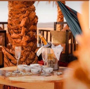 Luxury desert dinner setup at Dune Merzouga Camp Morocco with champagne and Berber-style dƩcor