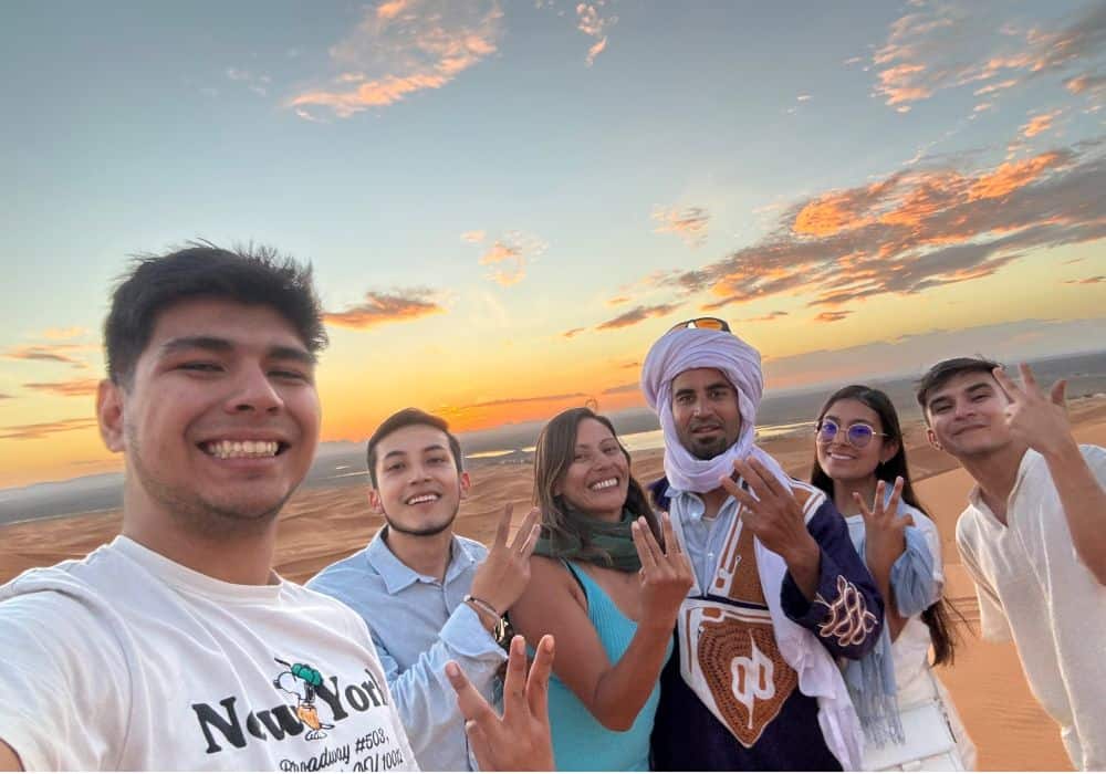 Tourists watching the sunset in Merzouga Sahara desert on a 2-day Fes tour Sunset Over the Merzouga Sahara Dunes