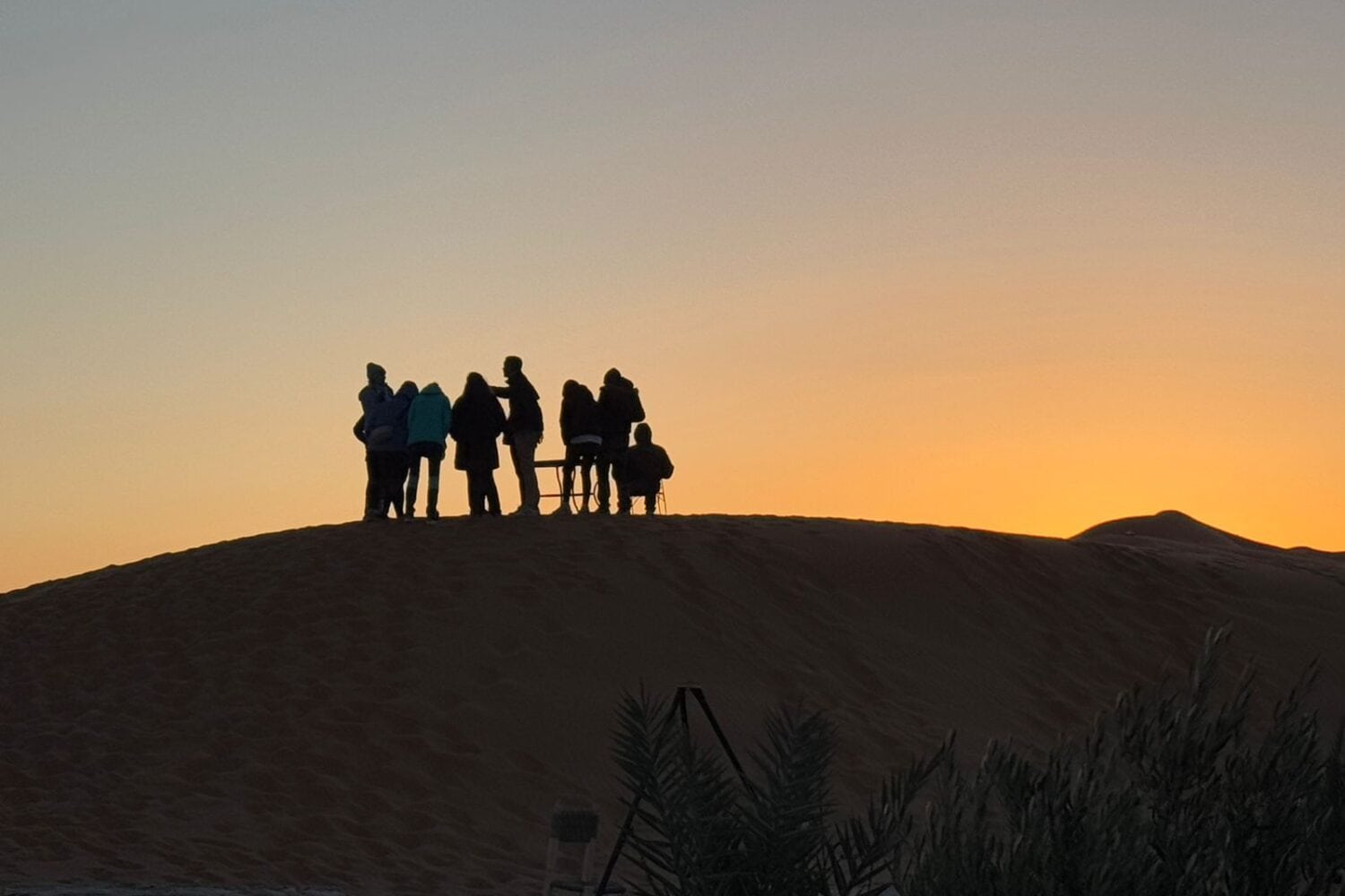 Exterior view of luxury desert tents at Dune Merzouga Camp surrounded by golden dunes in the Merzouga Desert.