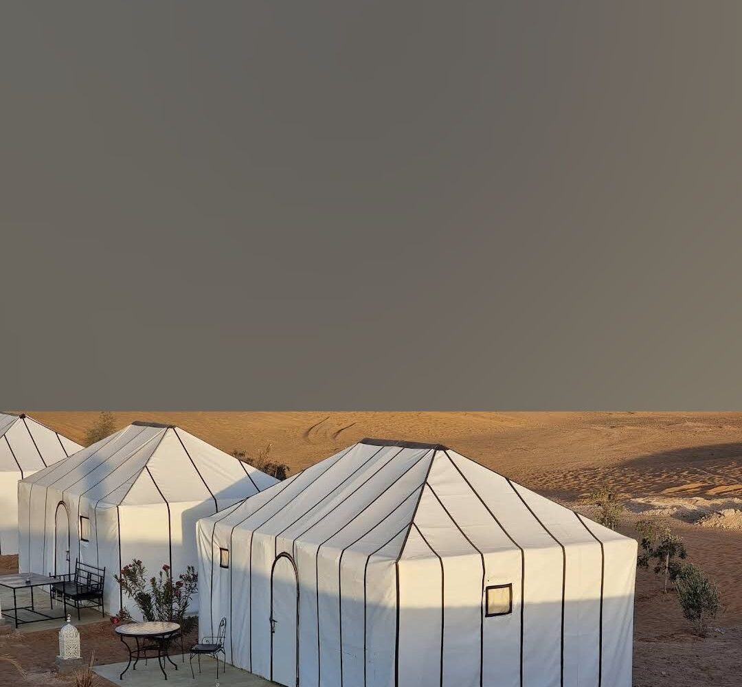 Exterior view of the Merzouga Desert Glamping Tent at Dune Merzouga Camp, surrounded by golden dunes in the Sahara Desert.