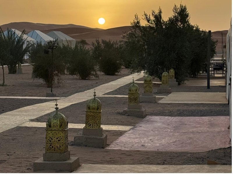Merzouga Luxury Camp tents and lanterns glowing at sunset in the Sahara.